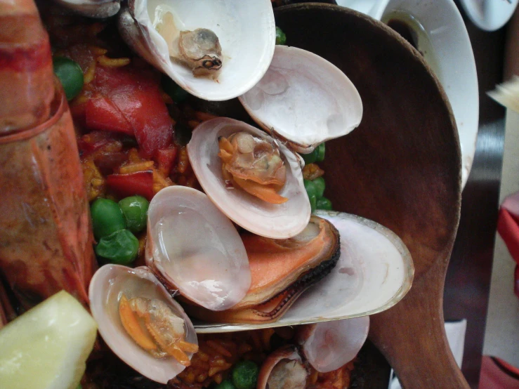 clams, peas and potatoes sitting on top of a brown bowl