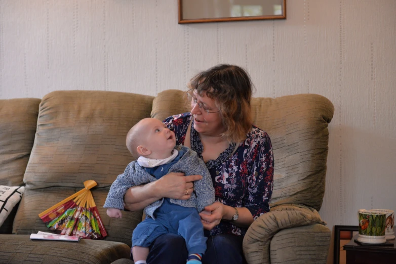 a woman holding a baby on a chair with her arm around her chest