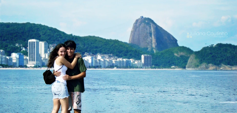two people are hugging in front of the water