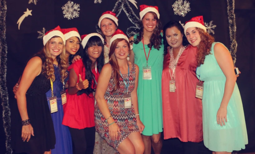 the woman are posing in a group together wearing christmas hats