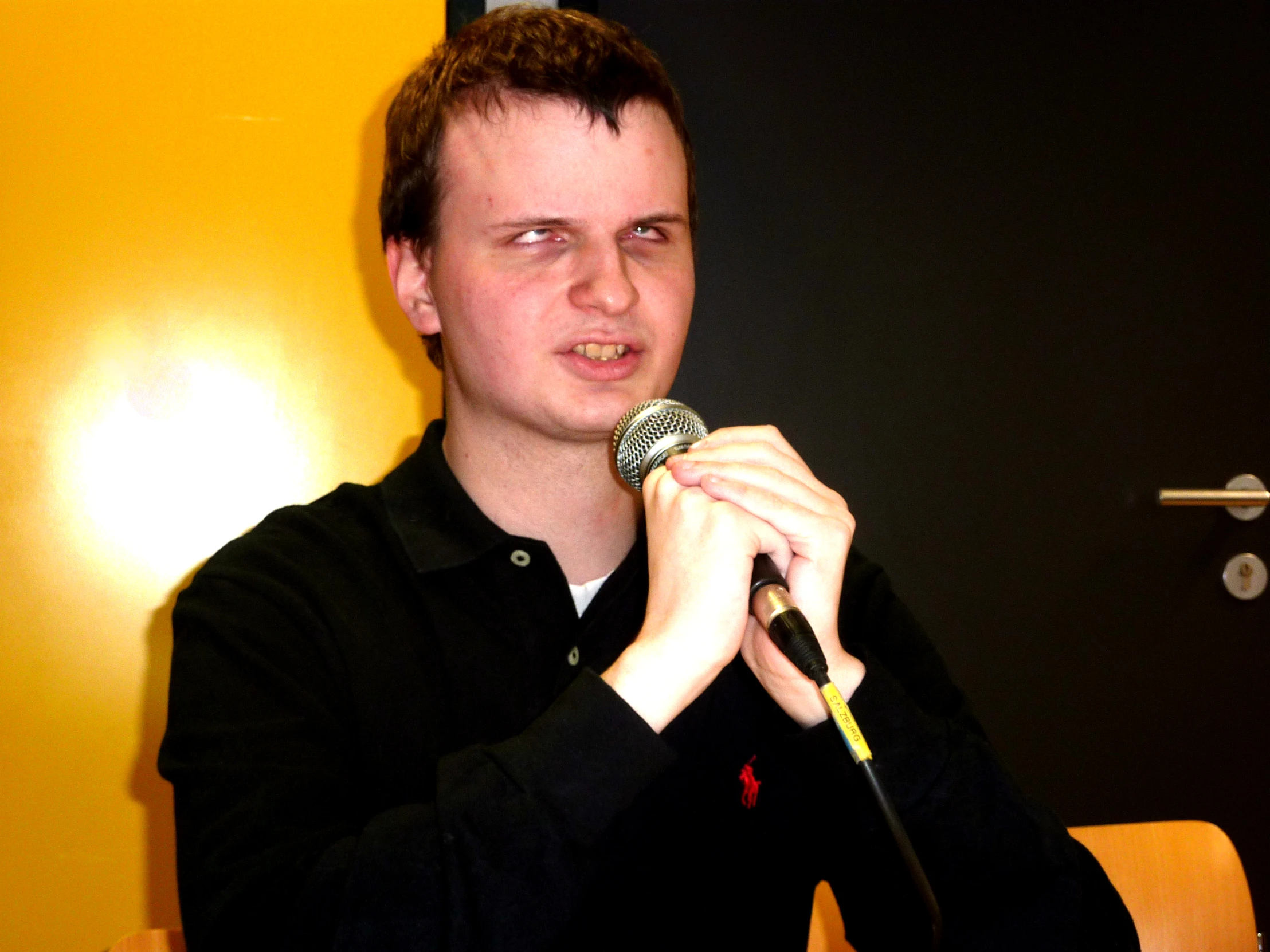 a young man holding a microphone to his right side