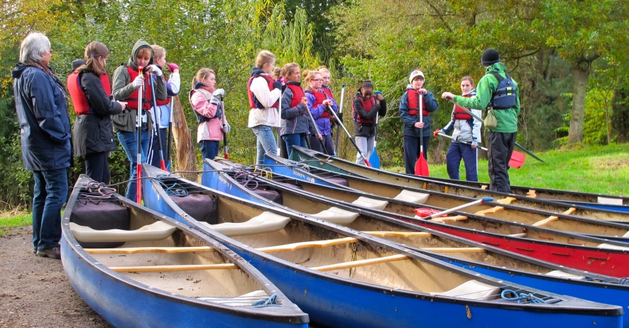 a group of people gather together to look at canoes