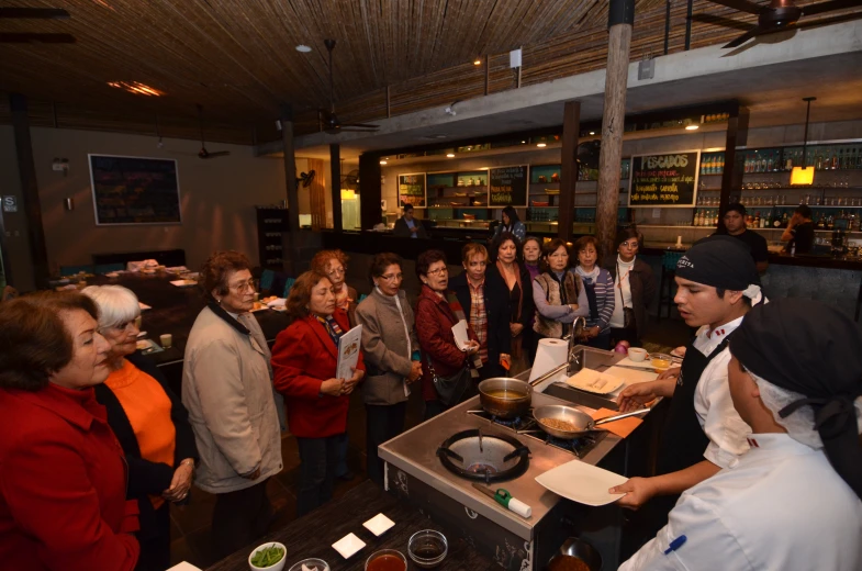 people in a crowded room watching woman cook