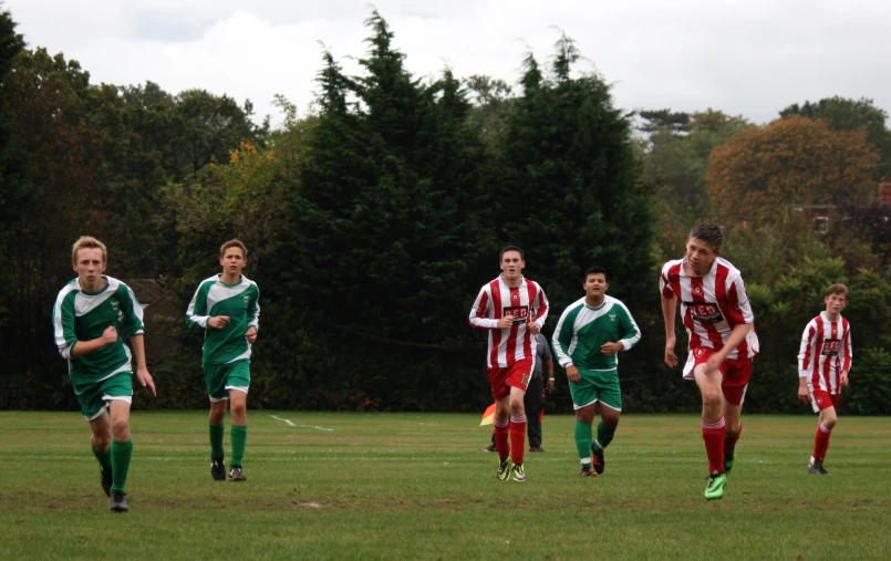 a group of young men playing soccer on top of a green field