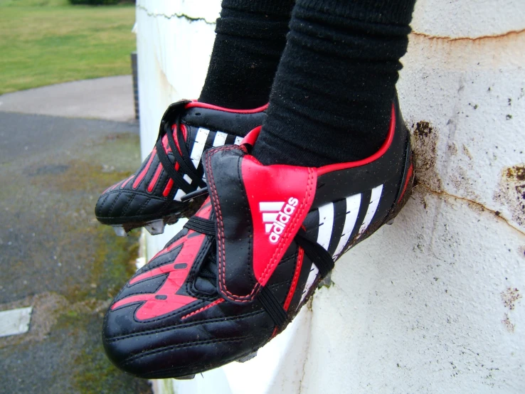 a person standing on a ledge and wearing adidas shoes