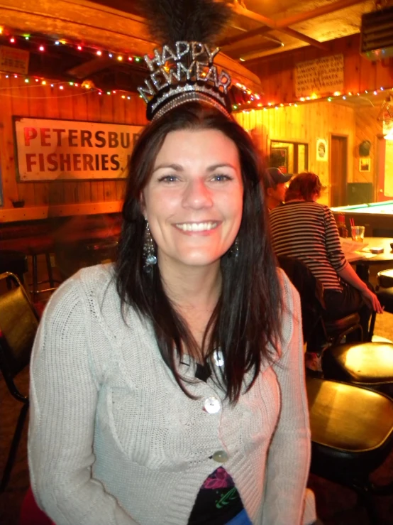 a woman sitting down at a restaurant with a tiara