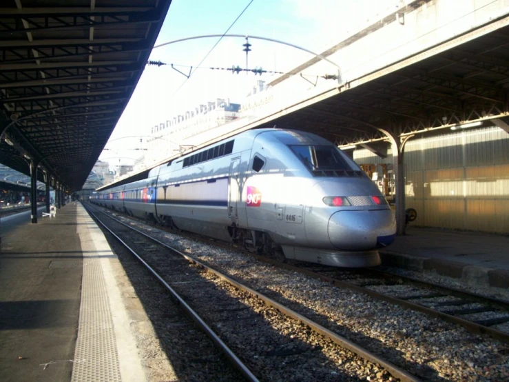 a silver train sitting on the tracks in a station