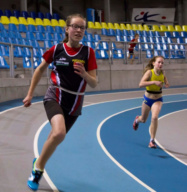 three female athletes running on blue and white track
