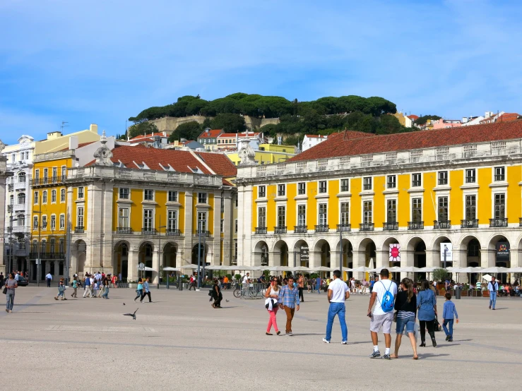 people walking in a courtyard at the base of a hill