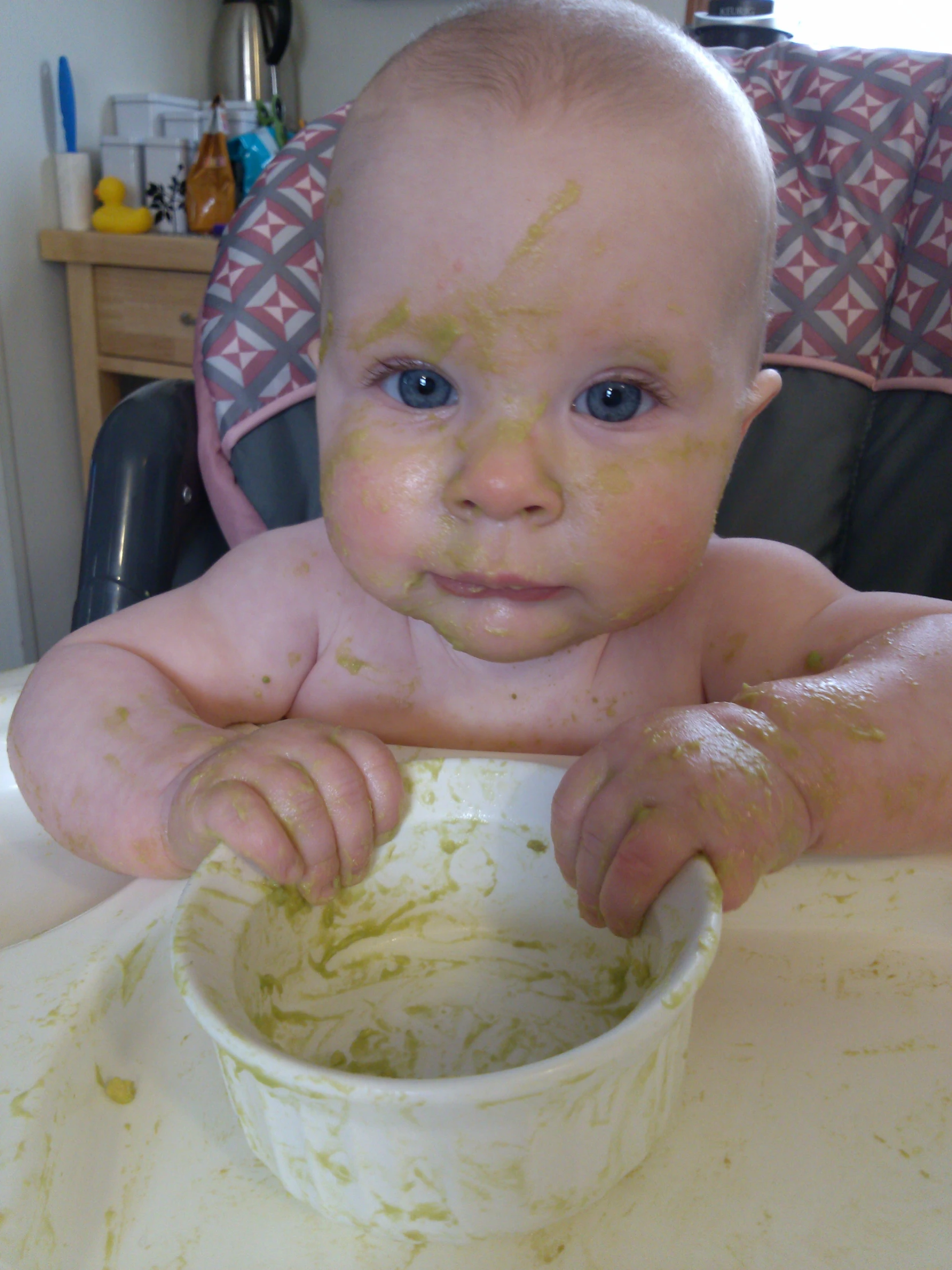 the baby is eating his food off of the bowl