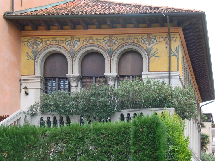 two windows on an elegant building above shrubbery