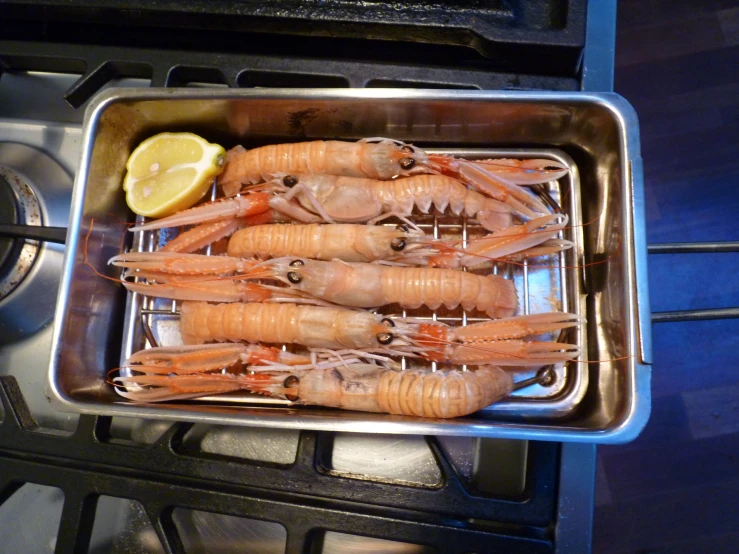 shrimp that are fried on a stove with lemon wedges