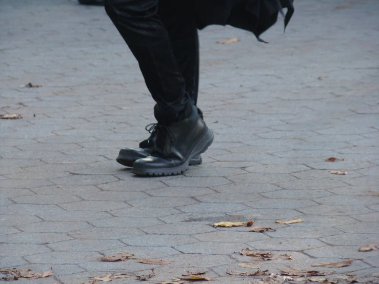 a person is walking on a brick surface wearing a jacket