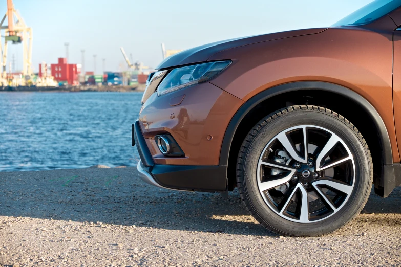 the front end of a brown nissan vehicle next to the ocean