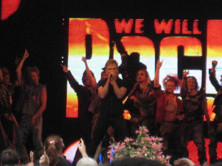 a group of people on a stage with a giant screen behind them