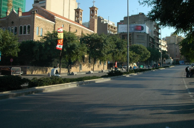 an empty street next to some buildings and people walking on it