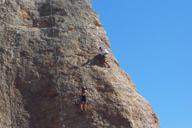 a man climbs up on a cliff to be lowered from a rope
