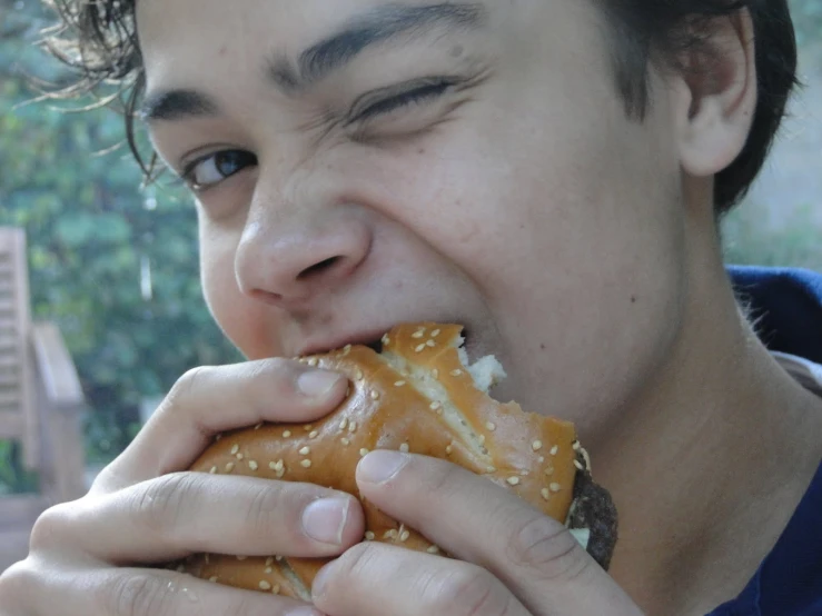 a young man with a beard eats a sandwich