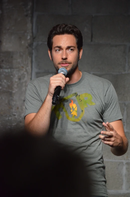 a man talking into a microphone near a brick wall