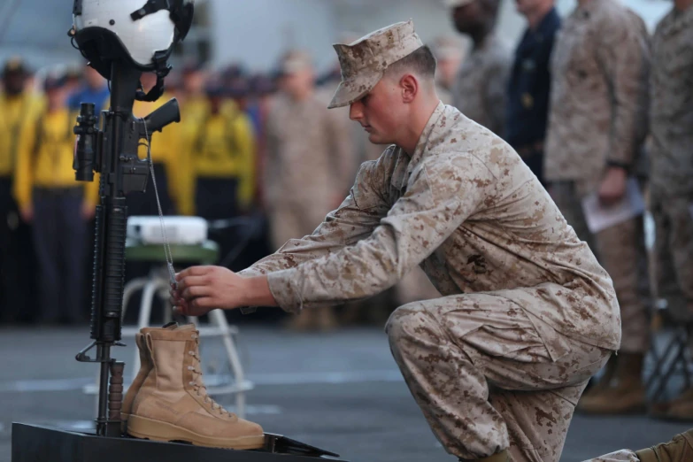 a soldier kneeling down to adjust a boot on a platform