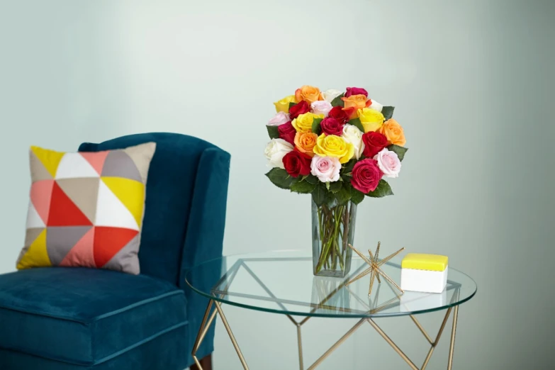 the vase with colorful flowers is sitting on the glass table next to a blue chair