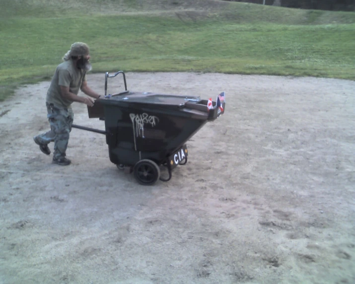 a man hing a wheelbarrow with a black trailer