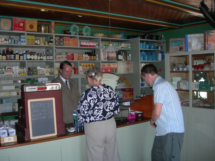 three people standing in front of the counter of a pharmacy