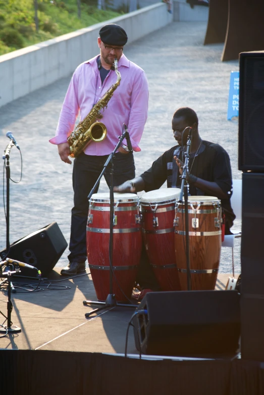 a man playing a musical instrument on stage next to a drummer