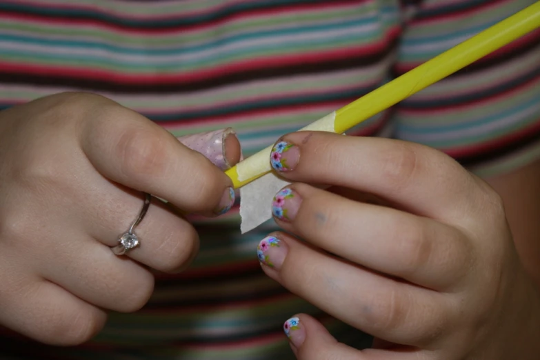 a woman holding a pen with nail polish and an eraser