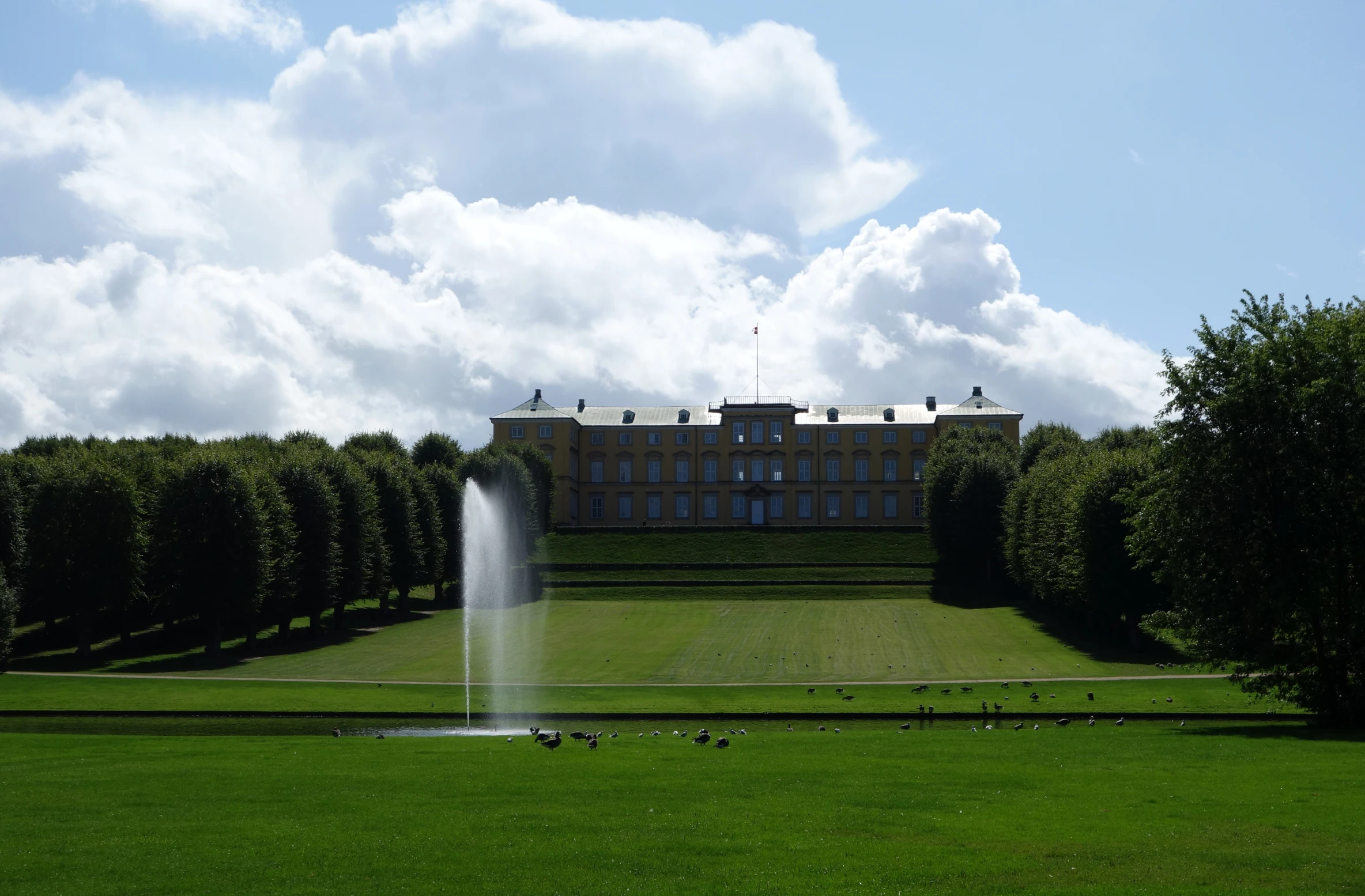 a large building with some trees and water spraying