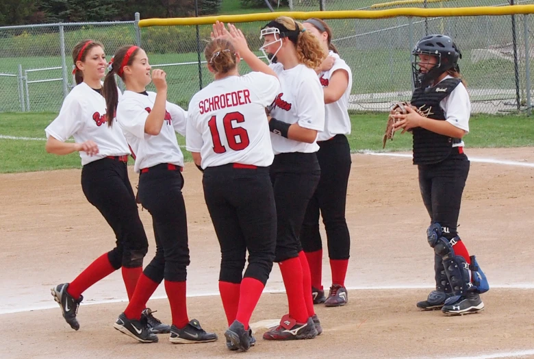 a softball team is on the field and greeting each other