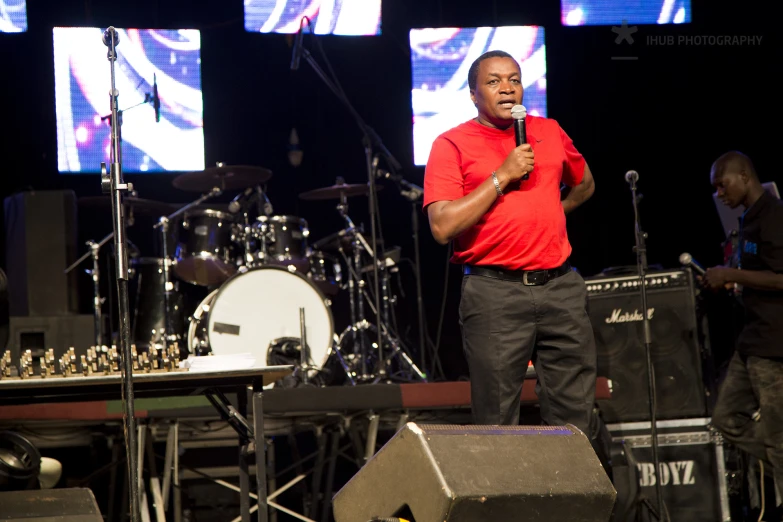 a man is standing on a stage with microphone in front of him