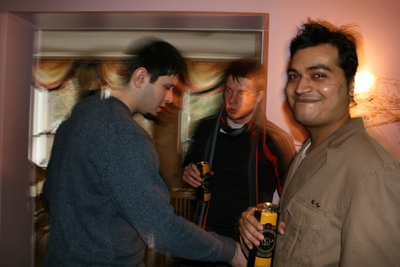 two guys standing in a hallway holding beer bottles