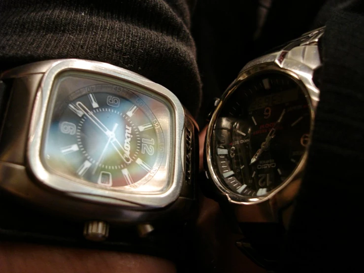 two mens watches are sitting on top of a mans hands