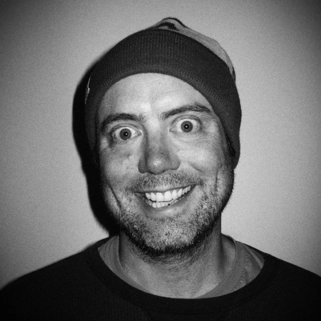 black and white pograph of smiling man in beanie