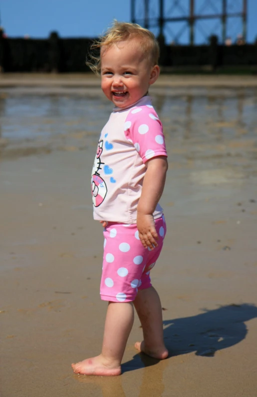 the toddler walks on the beach in her pajamas