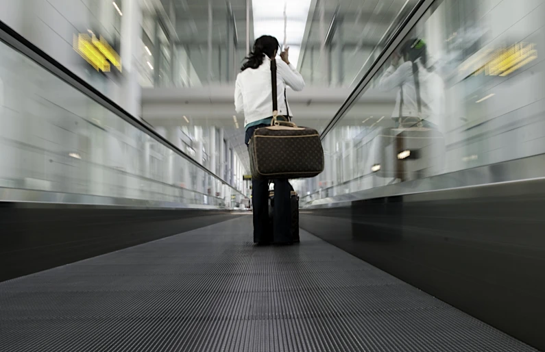 woman on cellphone with luggage in motion