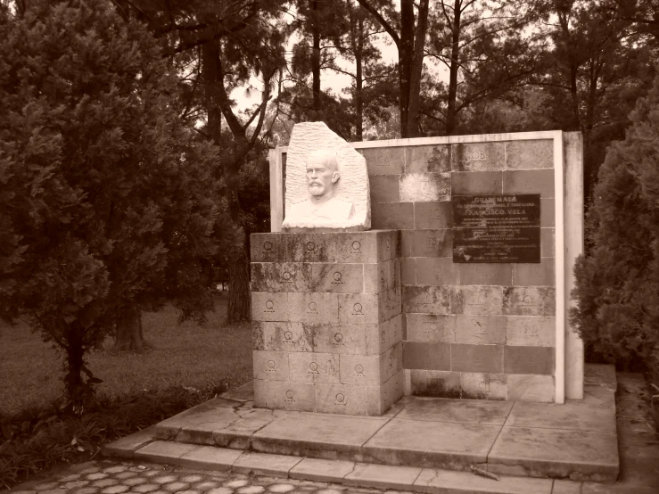 an old memorial sits on some steps surrounded by trees