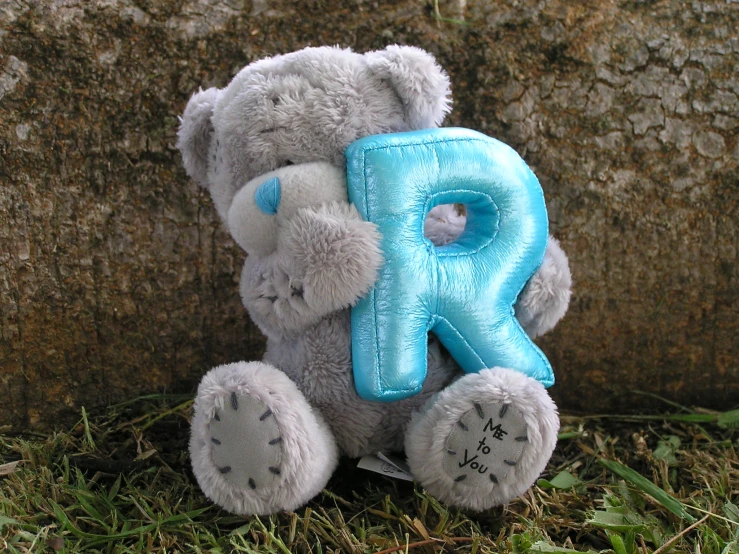 a gray and blue bear with letters k on it's back