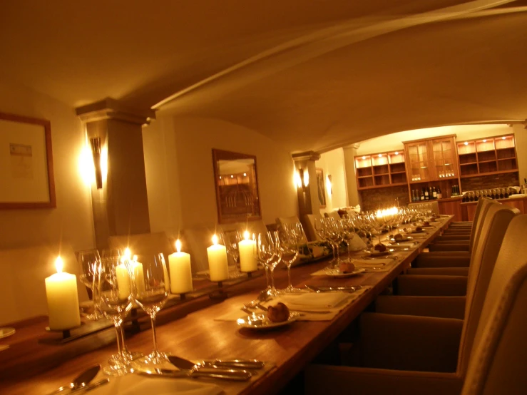 there is a large long table in the room with many lit candles