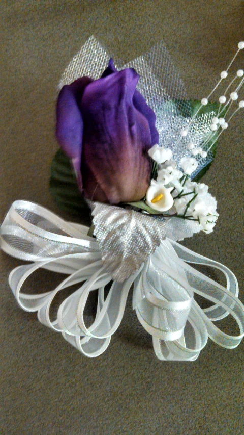 a purple rose with ribbon on a hat