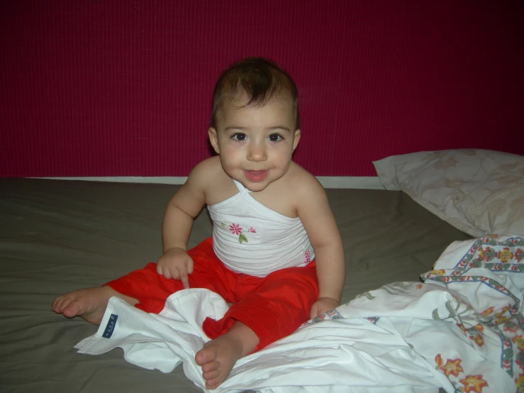 small child sitting on a bed with sheets and sheets