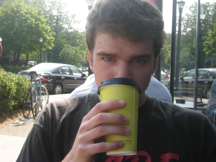 young man sipping and drinking from yellow cup