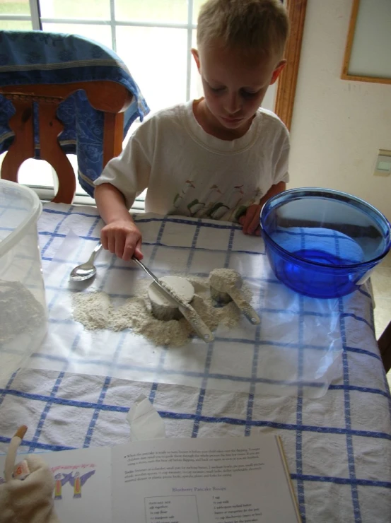 little boy in white shirt preparing food on table