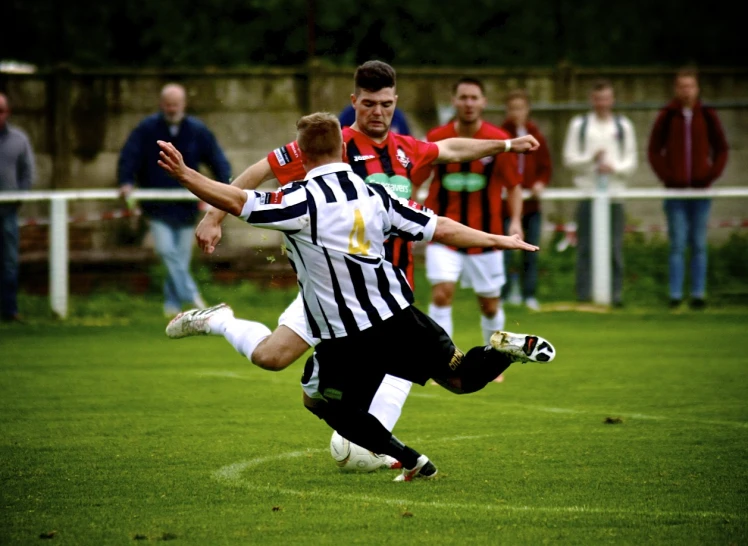 two young men in uniforms and white shorts, are fighting for the ball