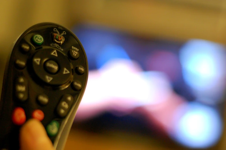 a hand holding up a remote control to a tv