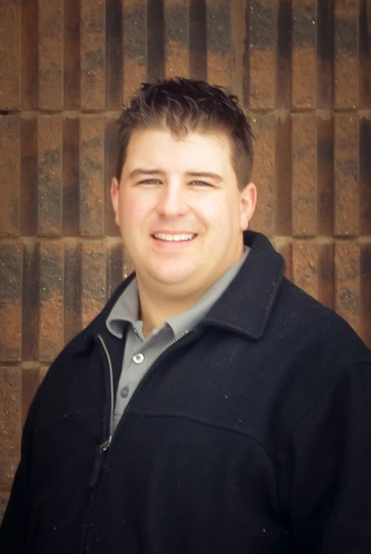 a person with a black jacket in front of a brick wall