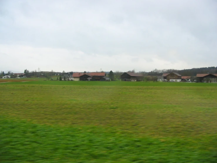 a green field with houses in the distance