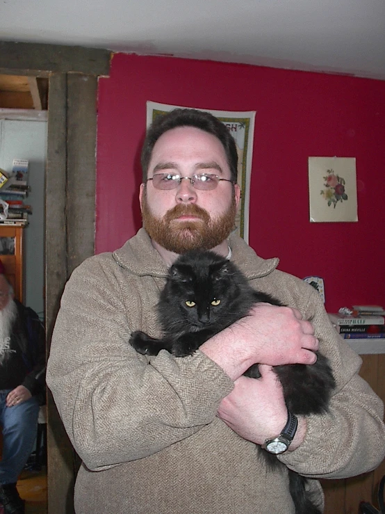 a bearded man with glasses and a beard holds a cat