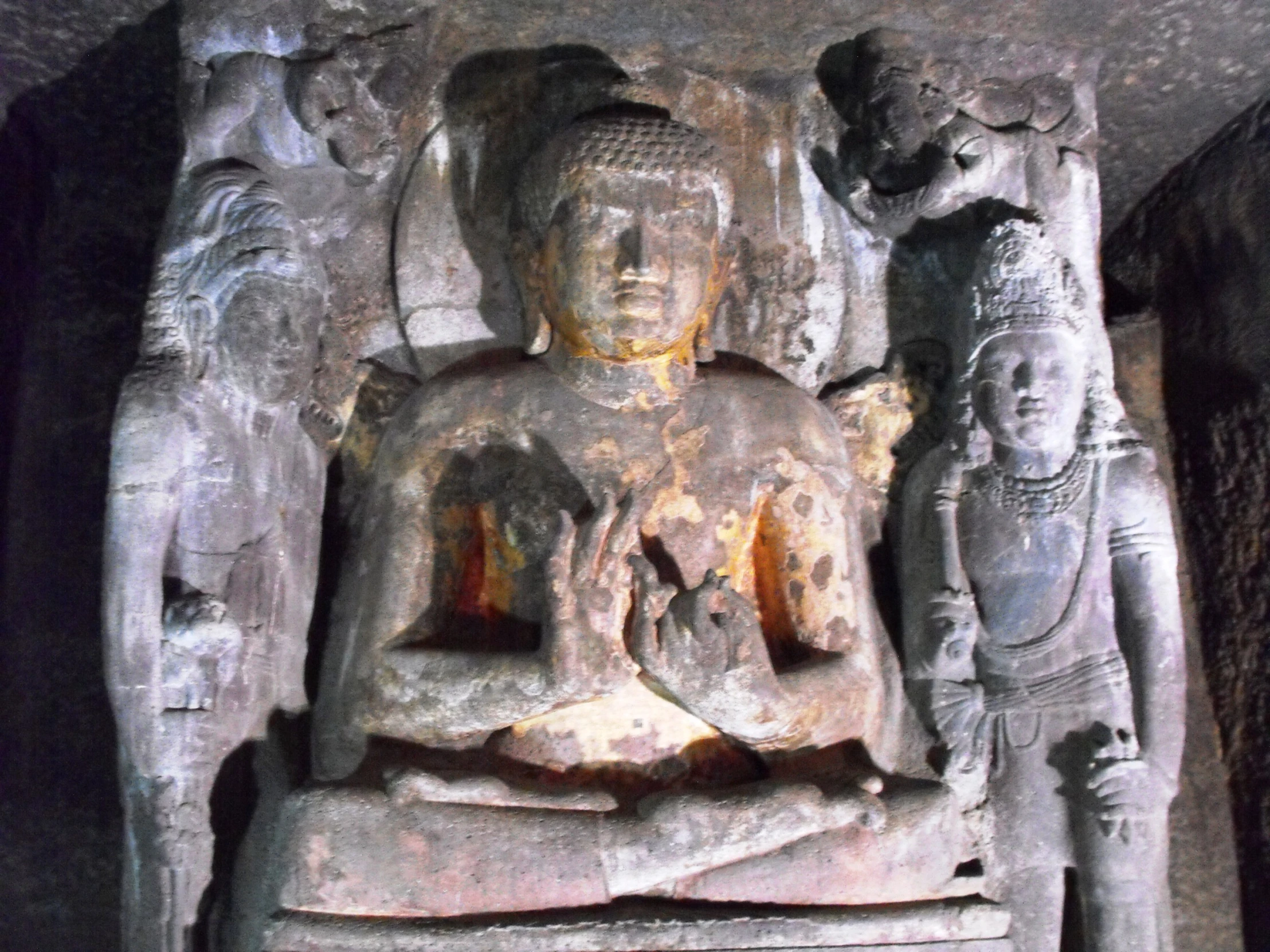 a buddha in a cave surrounded by sculptures